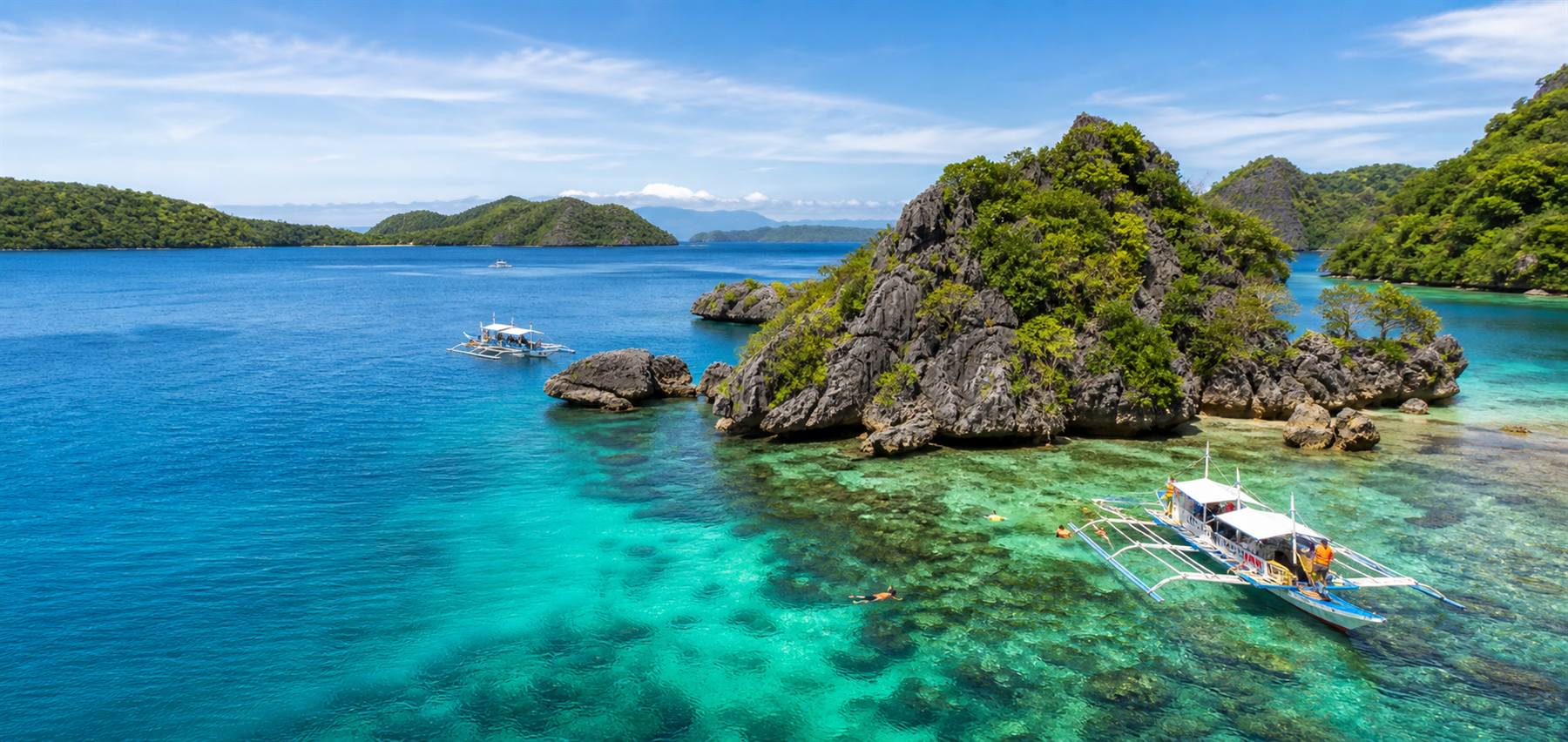 Island hopping scene around Boracay with blue lagoon water and boats